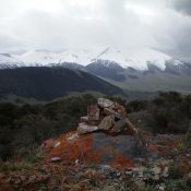 The summit cairn atop Peak 8256 with the snow-laden Pahsimeroi Range in the background on a stormy afternoon in May. Livingston Douglas Photo