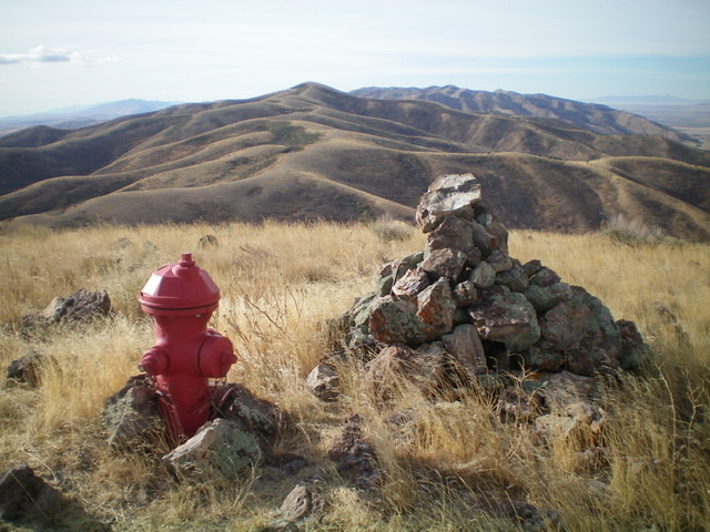 The red fire hydrant (a real one) and summit cairn atop Peak 6774, looking south. North Hansel Mountains HP is the pyramidal shaped summit in the distance (left of center). Livingston Douglas Photo 