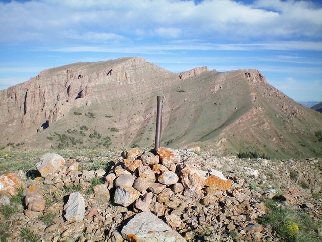 The summit cairn and ID/MT boundary post atop Knob Mountain. The Red Conglomerate Peaks are in the background. Livingston Douglas Photo 