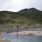 The Southeast Ridge of Arco Hills HP is on the left-half of the photo with Point 7352 being the forested, rocky outcrop just L of center. You cannot see the summit from here, it is behind Point 7352 by a good ¼ mile. The large, concrete-based cattle cistern which serves as the starting point for the Southeast Ridge Route. Livingston Douglas Photo