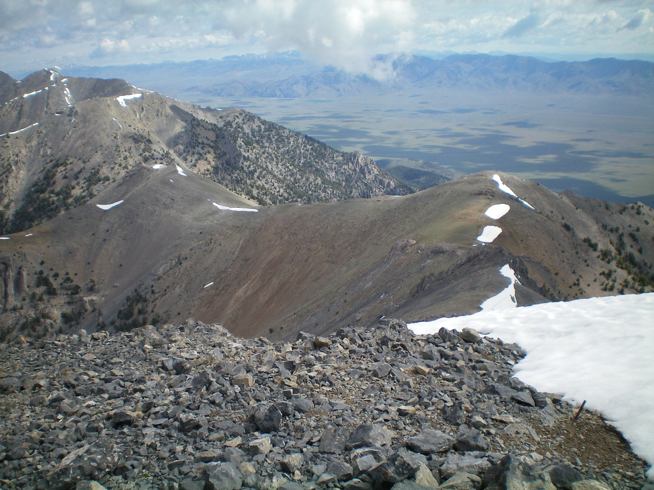 The upper section of the North Ridge/West Gully descent route, as viewed from the summit. Point 10196 is right of center. The saddle at the head of the West Gully is down the ridge from Point 10196 and is left of center with a thin lateral strip of snow near its top. The West Gully descends down and left from this saddle. There is steep, loose terrain in this section of the gully. Livingston Douglas Photo