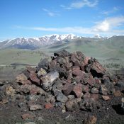 The large summit cairn atop the high point of North Crater in Craters of the Moon National Monument. Snow-clad Blizzard Mountain is in the distance. Livingston Douglas Photo