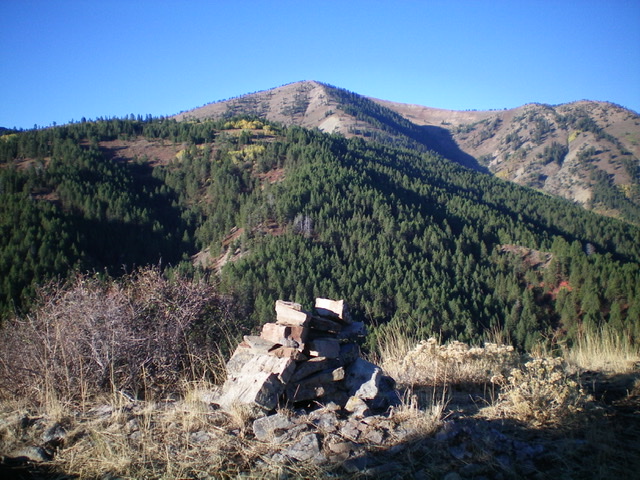 The summit cairn atop Peak 7314, looking southwest. Peak 7860 is the forested hump in mid-ground. Livingston Dough Photo 