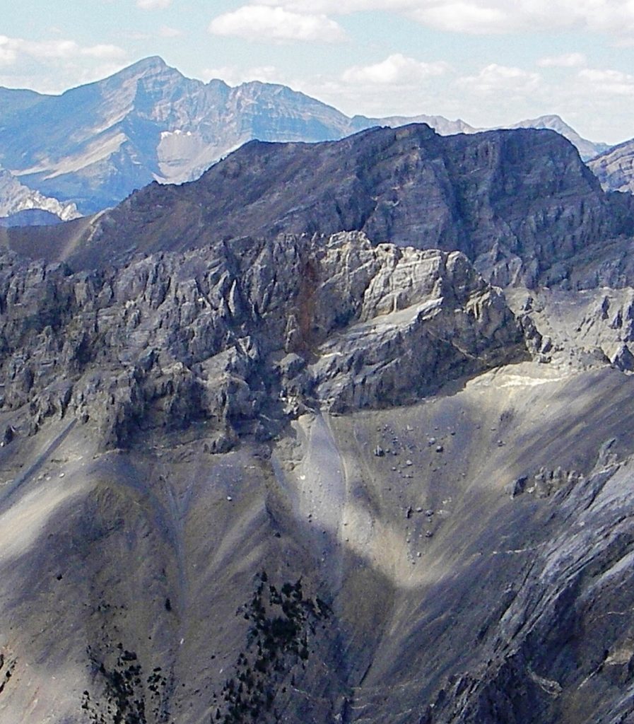 Looking NW from Ferguson Peak, the summit of True Grit is touched by the sun in the foreground. Cleft Peak rises in the mid-ground with Borah Peak in the distance. Judi Steciak Photo 