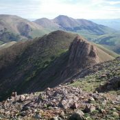 Divide Benchmark (gentle hump left of center) as viewed from Red Conglomerate Peaks South. The rocky outcrop just to the right of it must be skirted to keep this ridge traverse at Class 2. Livingston Douglas Photo