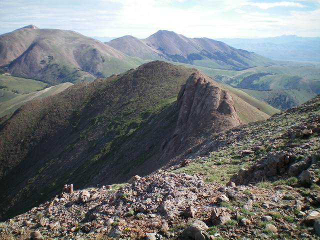 Divide Benchmark (gentle hump left of center) as viewed from Red Conglomerate Peaks South. The rocky outcrop just to the right of it must be skirted to keep this ridge traverse at Class 2. Livingston Douglas Photo 