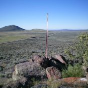 The summit cairn and summit post atop Magic Benchmark. Wedge Butte is in the distance, with ID-75 diagonally in between. Livingston Douglas Photo