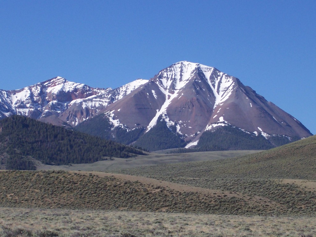 The view is SSW from Pahsimeroi Valley with Grouse Creek Mountain 11085' on left, and Sheep Pen Peak 10850' right. The low point on the 1.2 mile connecting ridge is 10500', giving Sheep Pen Peak a prominence of 350'. This summit has had 3 different spot elevations over the years. The 1935 Borah Peak 30 minute quad showed 10876'. The elevation was lowered on the 1956 Doublespring 15 min map to 10843'. The current elevation as shown on the 1989 Meadow Peak 7.5 min quad is 10850'.