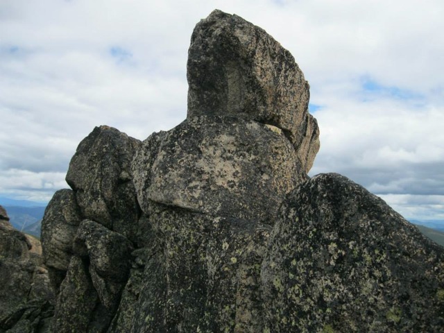 The summit block, with the “pull-up” ledge below the top, which one must use to traverse around to the left and up the last block. About 30-40 feet leading to death upon sharp rocks plunges off to the left. Dan Saxton Photo 